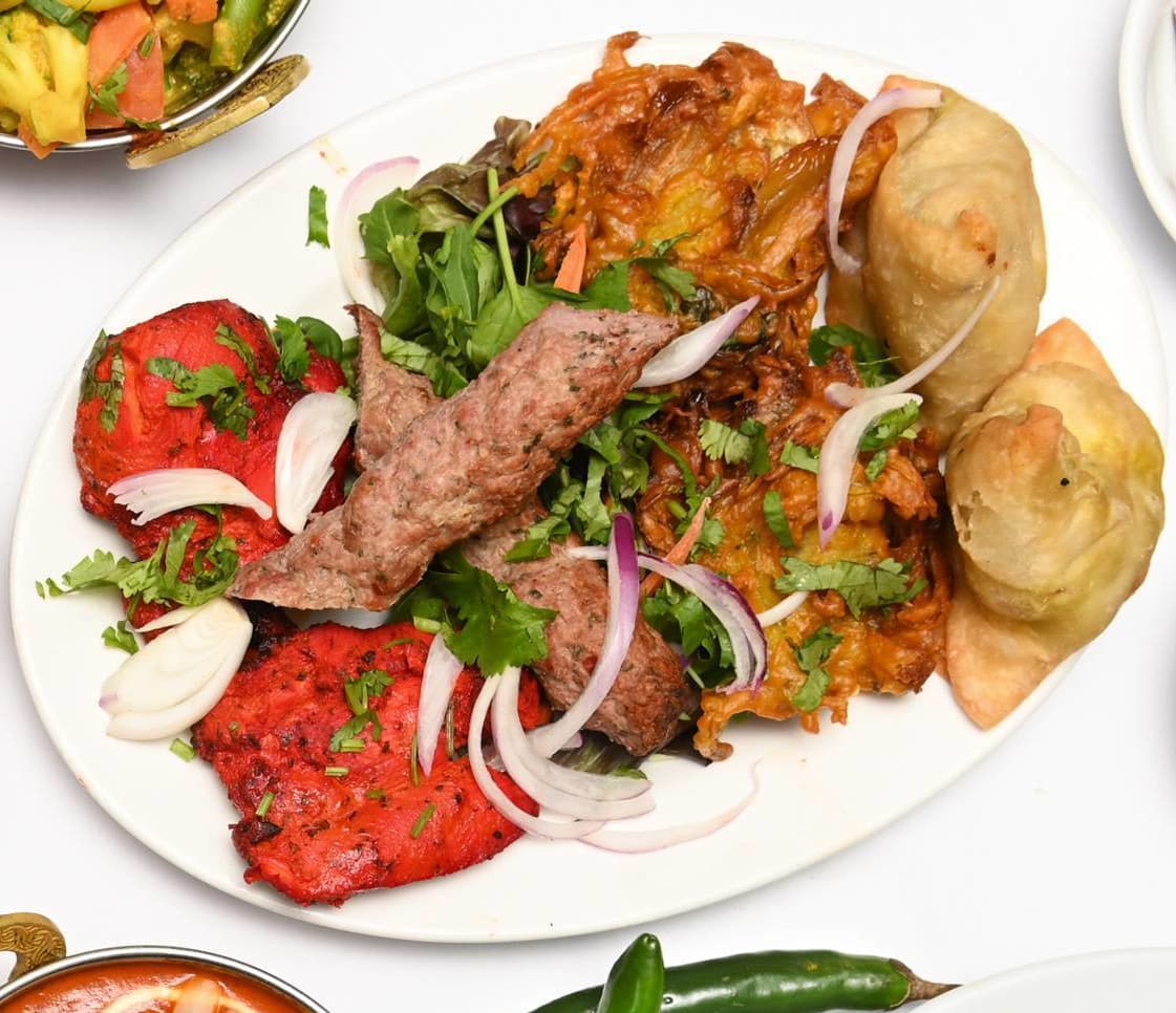 Mixed grill platter with seekh kebab, tandoori chicken, and samosa